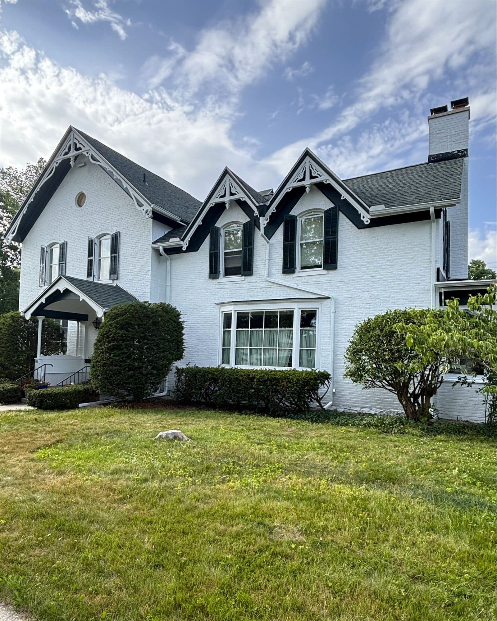White brick residential exterior with black shutters and freshly painted trim